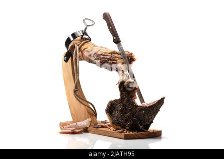 Jamon auf einem Holzständer zum Schneiden von Fleisch. Stück von Jamon auf Jamonero. Schinken, Jamon, Prosciutto. Studioaufnahme. Stockfoto