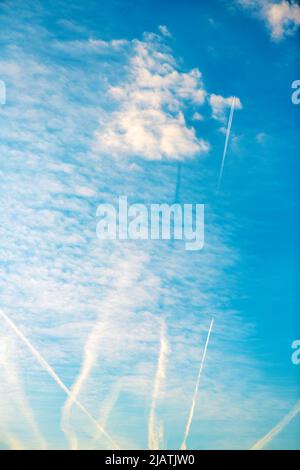 Dampfspur oder Kondensstreifen am blauen Himmel mit Wolken von unten Stockfoto