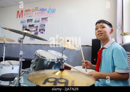 XINJI, 1. Juni 2022 (Xinhua) -- der Student Zhao Kangyuan spielt das Schlagzeug im Musikunterricht der Xinji Spezialschule in Xinji, nordchinesische Provinz Hebei, 31. Mai 2022. In der städtischen Spezialschule der Stadt Xinji, Provinz Hebei, schlägt eine Jazz-Trommler-Band namens „Against the Wind“ hoffnungsvolle Beats in der Welt der Stille. Die im Dezember 2018 gegründete Band beherbergt 10 Studenten mit Hörbehinderung oder geistiger Behinderung. Die Band wird seit ihrer Gründung systematisch und hart trainiert und die Bemühungen haben sich gelausgezahlt, als die Band verrückt wurde Stockfoto