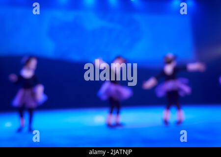 Unfokussierter abstrakter Hintergrund eines Tanzes aus einer Gruppe von Mädchen in der Anzahl von drei Personen. Hellblaue Bühnenbeleuchtung. Hochwertige Fotos Stockfoto