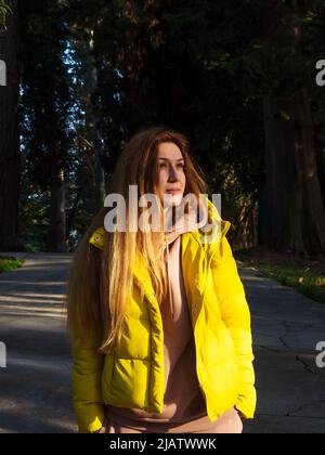 Frau Tourist zu Fuß in einem dichten Park entlang der Gasse an einem sonnigen Frühlingstag Stockfoto