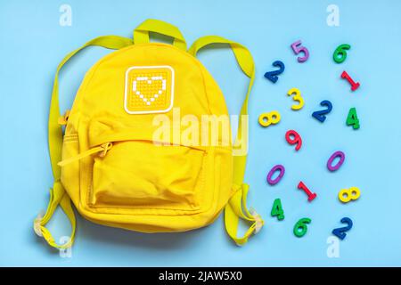 Zurück zur Schule, Bildungskonzept. Gelber Rucksack, Zahlen isoliert auf blauem Hintergrund. Draufsicht. Kopierbereich Flat Lay-Komposition. Stockfoto