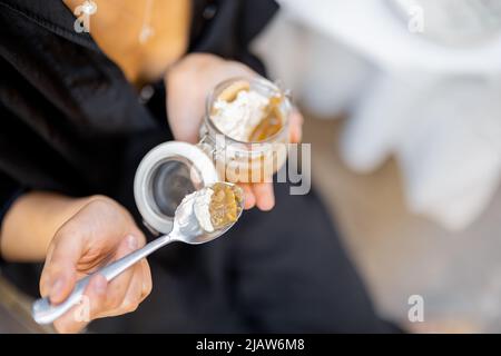 Frau, die im Restaurant im Freien Tiramisu-Dessert isst Stockfoto