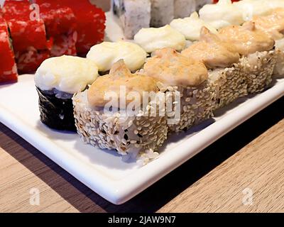 Brötchen mit Sesamtopf und Cremeplatte stehen auf weißer Schale. Ein Satz von mehreren Typen. Frisch zubereitete Brötchen. Nahaufnahme. Stockfoto