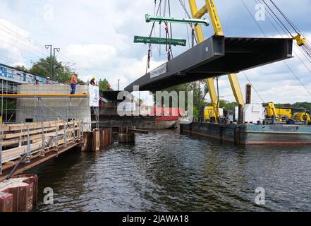 01. Juni 2022, Brandenburg, Werder (Havel): Der Mittelteil einer Brücke hängt vom Ausleger eines schwimmenden Krans, der auf dem Großen Zernsee unterwegs ist. Die künftige Fahrrad- und Fußgängerbrücke zwischen Werder (Havel) und Potsdam soll am 2. Juni 2022 fertiggestellt werden, wenn der letzte Stahlaufbau und die Aussichtsplattform angehoben werden. Foto: Soeren Sache/dpa Stockfoto