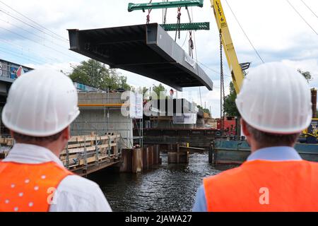 01. Juni 2022, Brandenburg, Werder (Havel): Der Mittelteil einer Brücke hängt vom Ausleger eines schwimmenden Krans, der auf dem Großen Zernsee unterwegs ist. Die künftige Fahrrad- und Fußgängerbrücke zwischen Werder (Havel) und Potsdam soll am 2. Juni 2022 fertiggestellt werden, wenn der letzte Stahlaufbau und die Aussichtsplattform angehoben werden. Foto: Soeren Sache/dpa Stockfoto