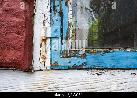 Altes schäbiges Holzfenster und ein Teil einer Ziegelwand. Details des historischen Tachwerkgebäudes. Stockfoto