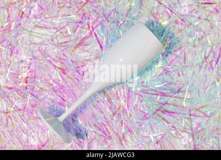 Sektglas auf hellem, farbenfrohem Hintergrund. Minimales Flat Lay Party Konzept. Schillernder Neonhintergrund. Holografische abstrakte weiche Farben. Stockfoto