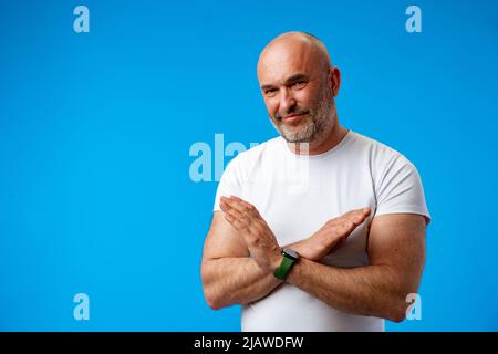 Schöner grauhaariger Mann aus dem mittleren Alter auf blauem Hintergrund, der Stoppschild macht Stockfoto