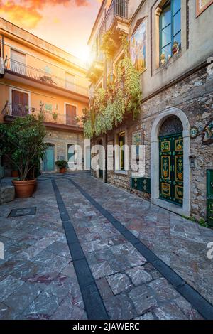 Schöne Altstadt von Taormina mit kleinen Straßen, Blumen. Architektur mit Bögen und alten Pflaster in Taormina. Bunte schmale Straße in der Altstadt o Stockfoto