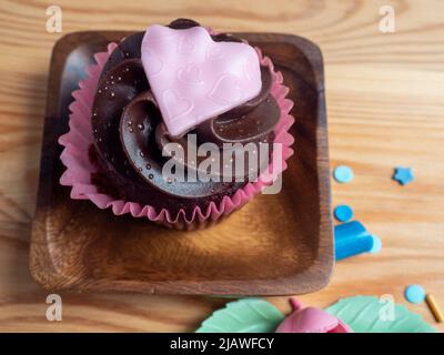 Cupcakes aus rotem Samt zum Valentinstag. Muffins für den Valentinstag auf einem hölzernen Hintergrund. Stockfoto