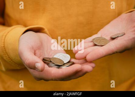 Russische Frau denkt an Sparkasse. Nur mans Hände und Geld, gelbe Kleidung. Konzept des armen Menschen. Russische Münzen halten in Händen und zählen. Krise Stockfoto