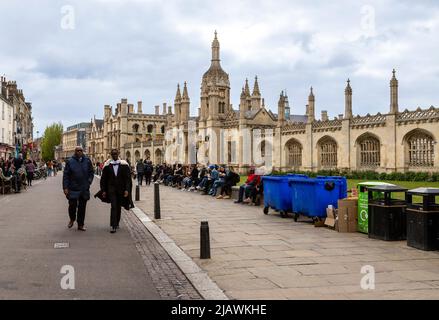 Student in traditioneller Kleidung am Graduation Day in Cambridge mit Blick auf das King’s College Gatehouse und die Leinwandwand, Cambridgeshire, England, Großbritannien. Stockfoto