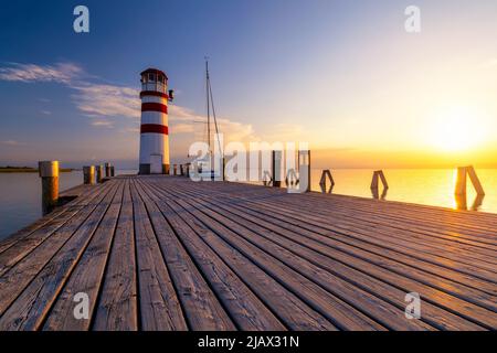 Leuchtturm am Neusiedler See, Podersdorf am See, Burgenland, Österreich. Leuchtturm bei Sonnenuntergang in Österreich. Hölzerne Seebrücke mit Leuchtturm in Podersdorf auf Lak Stockfoto