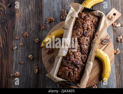 Bananenbrot mit Walnussauflage auf Holztisch. Draufsicht mit Kopierbereich Stockfoto