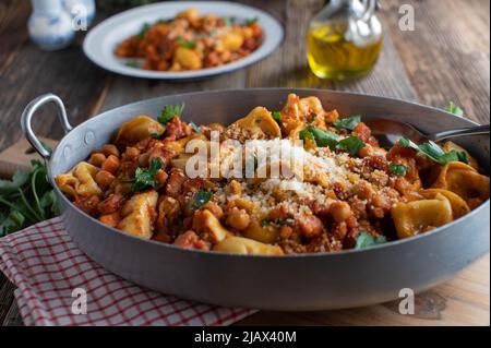 Kichererbsengericht mit Tortellini, Pancetta, Gemüse in einer köstlichen Tomatensauce. Serviert mit Parmesankäse. Stockfoto