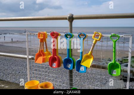 Bunte Plastikeimer und -Pik zum Verkauf an der Promenade in Sheringham, Norfolk, England Stockfoto
