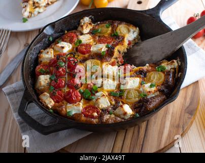 Frittata mit Tomaten, Paprika, Zwiebeln und Feta-Käse in einer rustikalen Pfanne Stockfoto