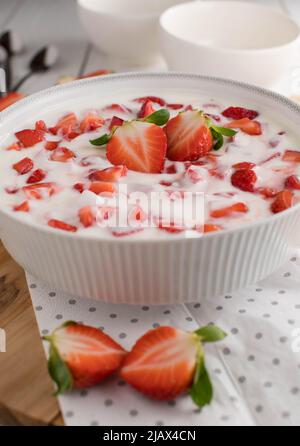 Gesundes Dessert mit frisch gehackten Erdbeeren und Bio-Joghurt in einer weißen Schüssel auf dem Küchentisch Stockfoto