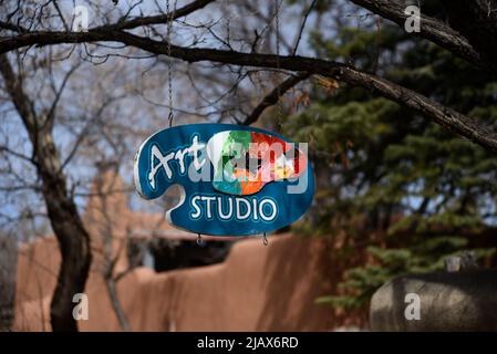 Ein Schild in Form einer Künstlerpalette hängt vor einem Kunststudio in Santa Fe, New Mexico. Stockfoto