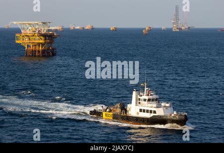 Ölbohrinseln mit Versorgungsboot für den Transport von Menschen oder Materialien zu nahe gelegenen Bohrinseln, Südchinesisches Meer, Malaysia Stockfoto