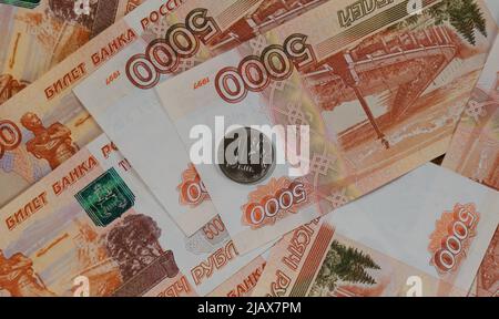 Russische Papierbanknoten im Wert von 5.000 Rubel aus der Nähe und eine Münze 1 Rubel in der mittleren Ansicht von oben. Wirtschaft und Finanzen der Russischen Föderation. Große Stockfoto