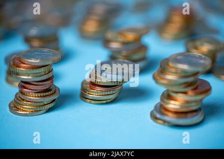 Euro-Münzen zu Türmen aufgeschichtet. Münzen auf blauem Hintergrund. EUR-Währung aus der Europäischen Union Stockfoto
