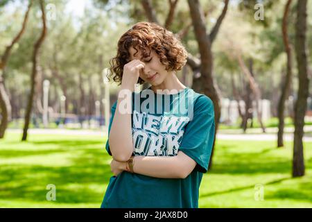 Junge Rothaarige Frau trägt lässiges grünes T-Shirt Reiben Nase und Augen Gefühl Müdigkeit und Kopfschmerzen. Stress und Frustration Konzept. Massieren Nase br Stockfoto