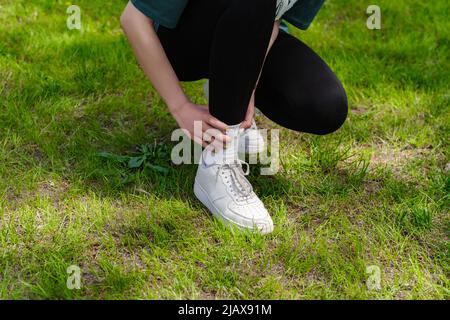 Verkürzte Ansicht einer jungen Läuferin, die schwarze Leggings trägt und beim Training und Laufen an einem Knöchel verletzt ist. Gesundheits- und Sportkonzept. Stockfoto