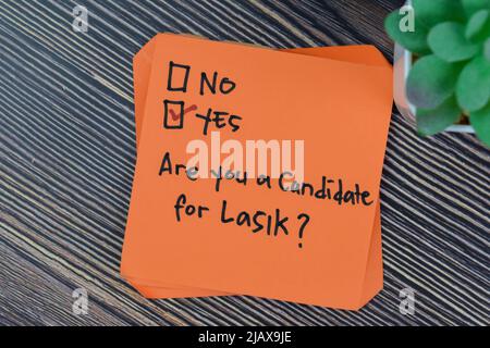 Konzept von sind Sie ein Kandidat für Lasik? Ja, schreiben Sie auf Haftnotizen, die auf einem Holztisch isoliert sind. Stockfoto