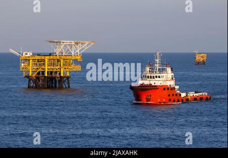 Ölbohrinseln mit Versorgungsboot für den Transport von Menschen oder Materialien zu nahe gelegenen Bohrinseln, Südchinesisches Meer, Malaysia Stockfoto