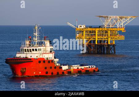 Ölbohrinseln mit Versorgungsboot für den Transport von Menschen oder Materialien zu nahe gelegenen Bohrinseln, Südchinesisches Meer, Malaysia Stockfoto