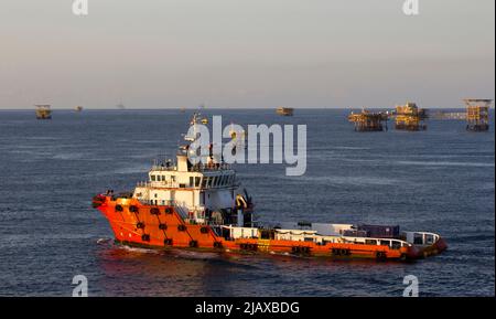 Ölbohrinseln mit Versorgungsboot für den Transport von Menschen oder Materialien zu nahe gelegenen Bohrinseln, Südchinesisches Meer, Malaysia Stockfoto