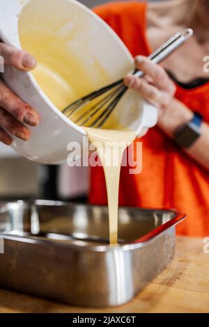 Frau gießt flüssiges Mousse in eine Form. Stockfoto