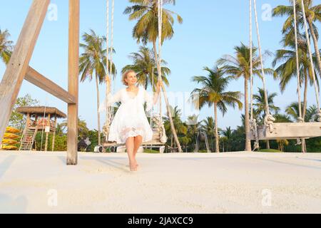 Eine Frau schwingt auf einer Schaukel am Strand. Stockfoto