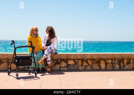 Mutter und Großmutter schlendern am Strand entlang Stockfoto
