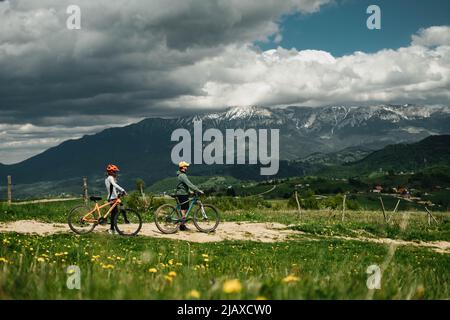 Ein junges Paar Radfahrer hält ihre Fahrräder gegen die Berge Stockfoto