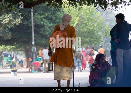 Sadhu Mönch trägt die Safranroben heilig zum hinduismus und eine Tasche mit heiligen Symbolen beim Gehen unter den Menschen am Ufer des heiligen Flusses ganga Stockfoto