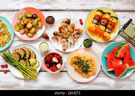 Gesunde Pflanze basierte Sommer bbq Tischszene. Draufsicht auf weißem Holzhintergrund. Obst, gegrilltes Gemüse, Spieße, Blumenkohlsteak und Limonade. M Stockfoto