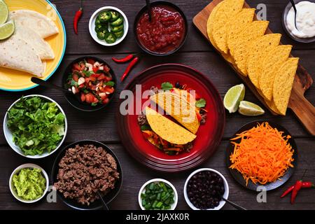 Taco Bartisch-Szene mit einer Auswahl an Zutaten. Oben auf einem dunklen Holzbanner Hintergrund. Mexikanisches Buffet. Stockfoto