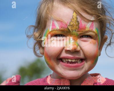Junges Mädchen mit Gesicht gemalt glücklich und lächelnd, Großbritannien Stockfoto