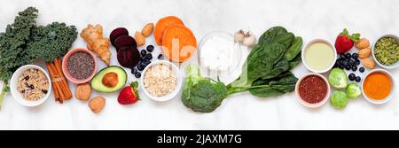 Set von gesunden Lebensmitteln Zutaten. Draufsicht Tischszene auf weißem Marmorbanner Hintergrund. Super-Food-Konzept mit grünem Gemüse, Beeren, ganze gr Stockfoto