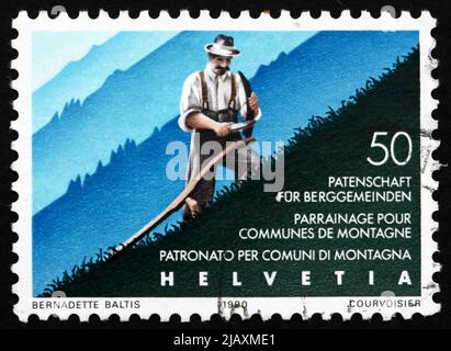 SCHWEIZ - UM 1990: Eine in der Schweiz gedruckte Marke zeigt Mountain Farmer Cuts Grass, Assistance for Mountain Communities, 50. Anniversary, Stockfoto