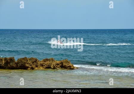 Denia, Alicante, Spanien - 20 2021. Juli: Zwei Rettungsschwimmer fahren auf einem orangefarbenen Jetski in den Wellen der spanischen Küste mit Blick auf den Horizont und das O Stockfoto