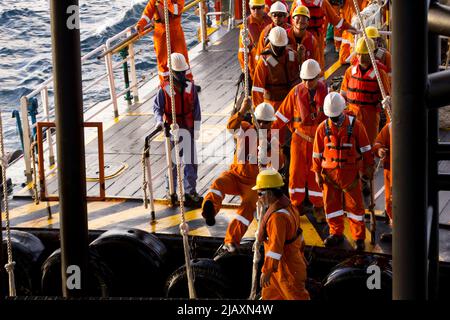 Rig-Arbeiter werden auf einem Schiff zu Offshore-Bohrinseln im Südchinesischen Meer, Brunei, transportiert. Ein Schaukelseil wird verwendet, um die Plattform zu betreten Stockfoto