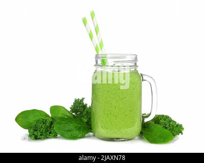 Grüner Smoothie mit Grünkohl und Spinat in einem Einmachglas. Seitenansicht mit isolierten Zutaten auf weißem Hintergrund. Stockfoto