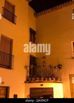 Denia, Alicante, Spanien - Juli 17 2021: Kleiner Eckbalkon eines weißen spanischen Hauses, dekoriert mit einigen Topfpflanzen im Licht einer Laterne Stockfoto