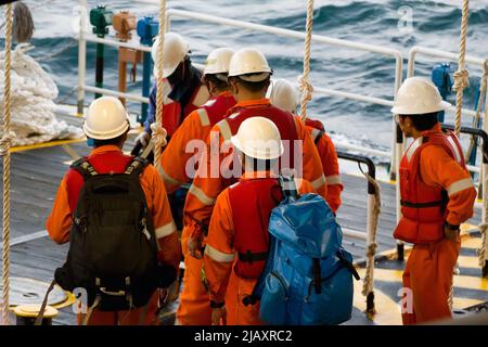 Rig-Arbeiter werden auf einem Schiff zu Offshore-Bohrinseln im Südchinesischen Meer, Brunei, transportiert. Ein Schaukelseil wird verwendet, um die Plattform zu betreten Stockfoto