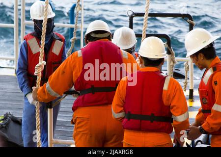 Rig-Arbeiter werden auf einem Schiff zu Offshore-Bohrinseln im Südchinesischen Meer, Brunei, transportiert. Ein Schaukelseil wird verwendet, um die Plattform zu betreten Stockfoto