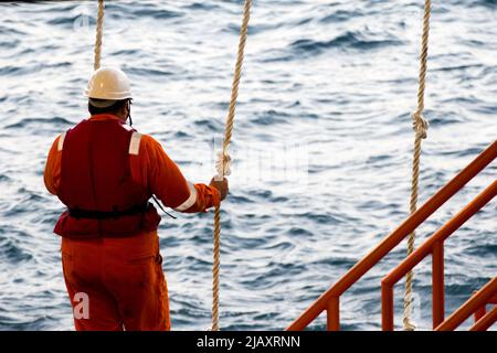 Rig-Arbeiter werden auf einem Schiff zu Offshore-Bohrinseln im Südchinesischen Meer, Brunei, transportiert. Ein Schaukelseil wird verwendet, um die Plattform zu betreten Stockfoto